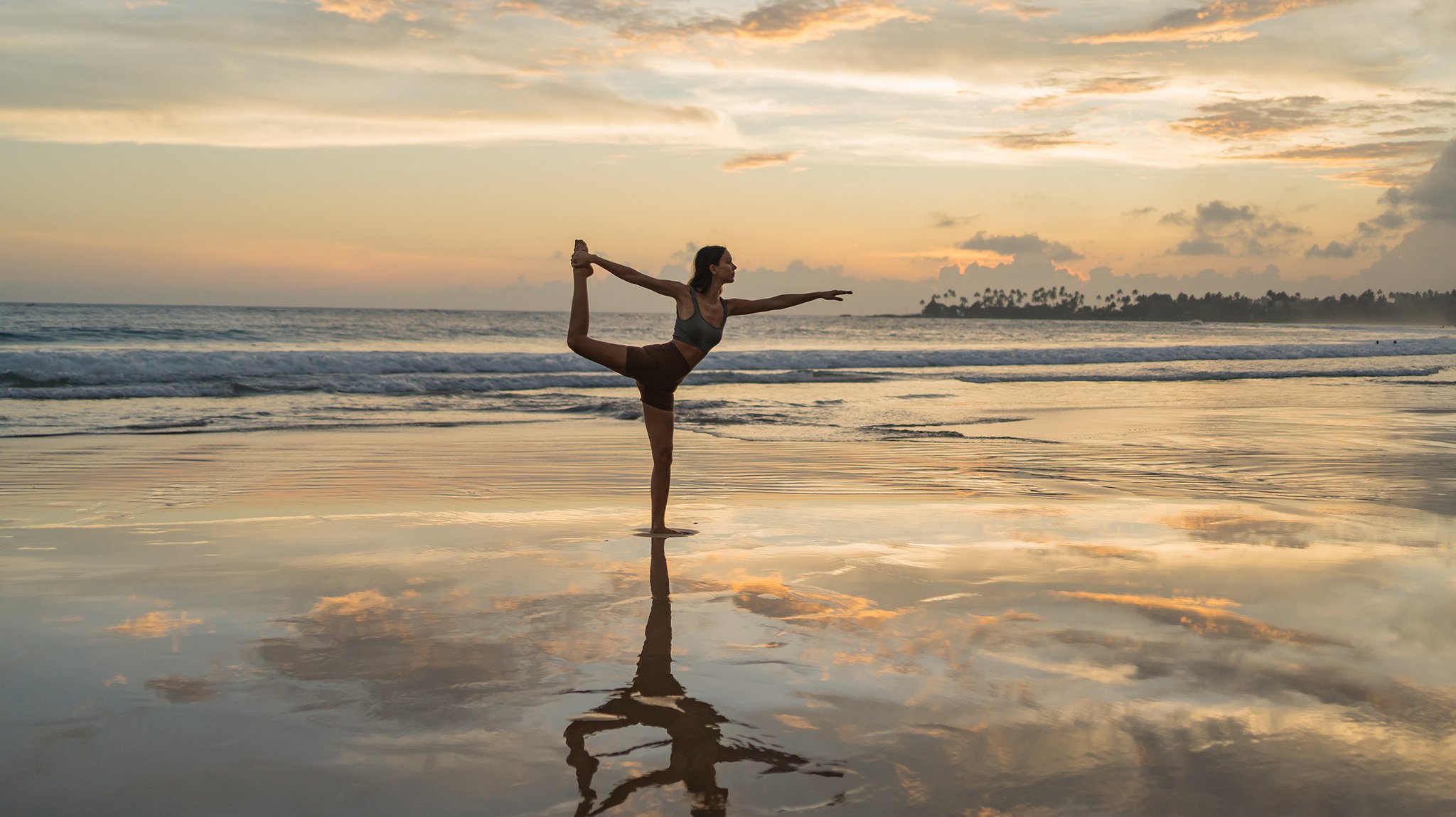 A woman doing yoga near the water.