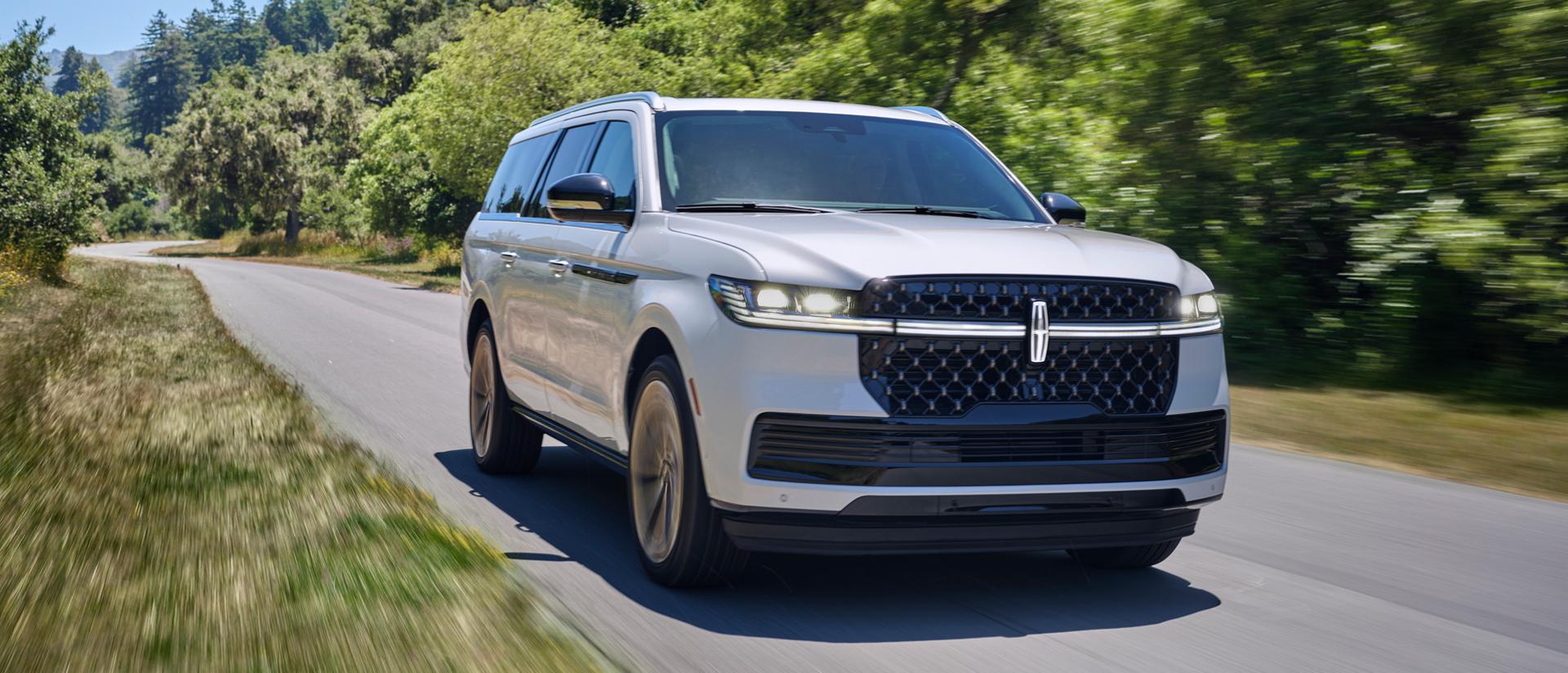 A 2026 Lincoln Navigator® SUV is being driven on a country road