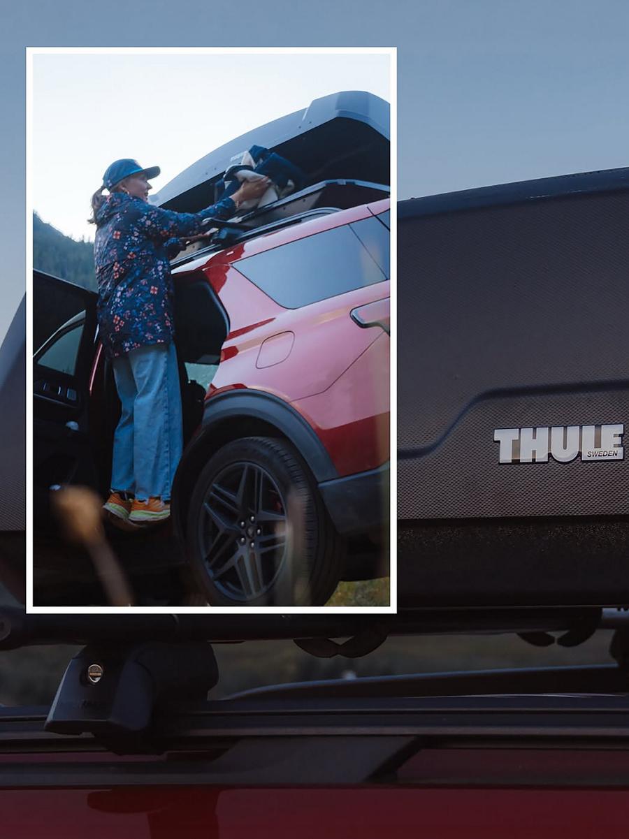 A red 2025 Ford Explorer® parked with a person grabbing something from the roof cargo box