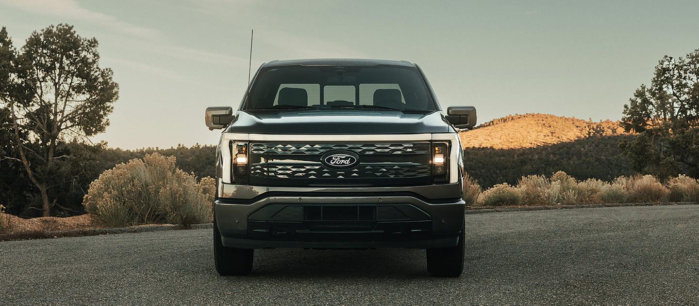 A 2025 Ford F-150® Lightning® in Carbonized Gray parked with a hilly terrain in the background