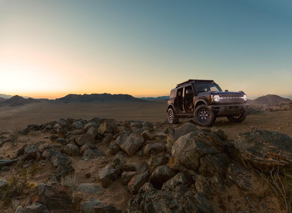 Una Ford Bronco® Badlands® 2025 estacionada en un camino de tierra con montañas en la distancia