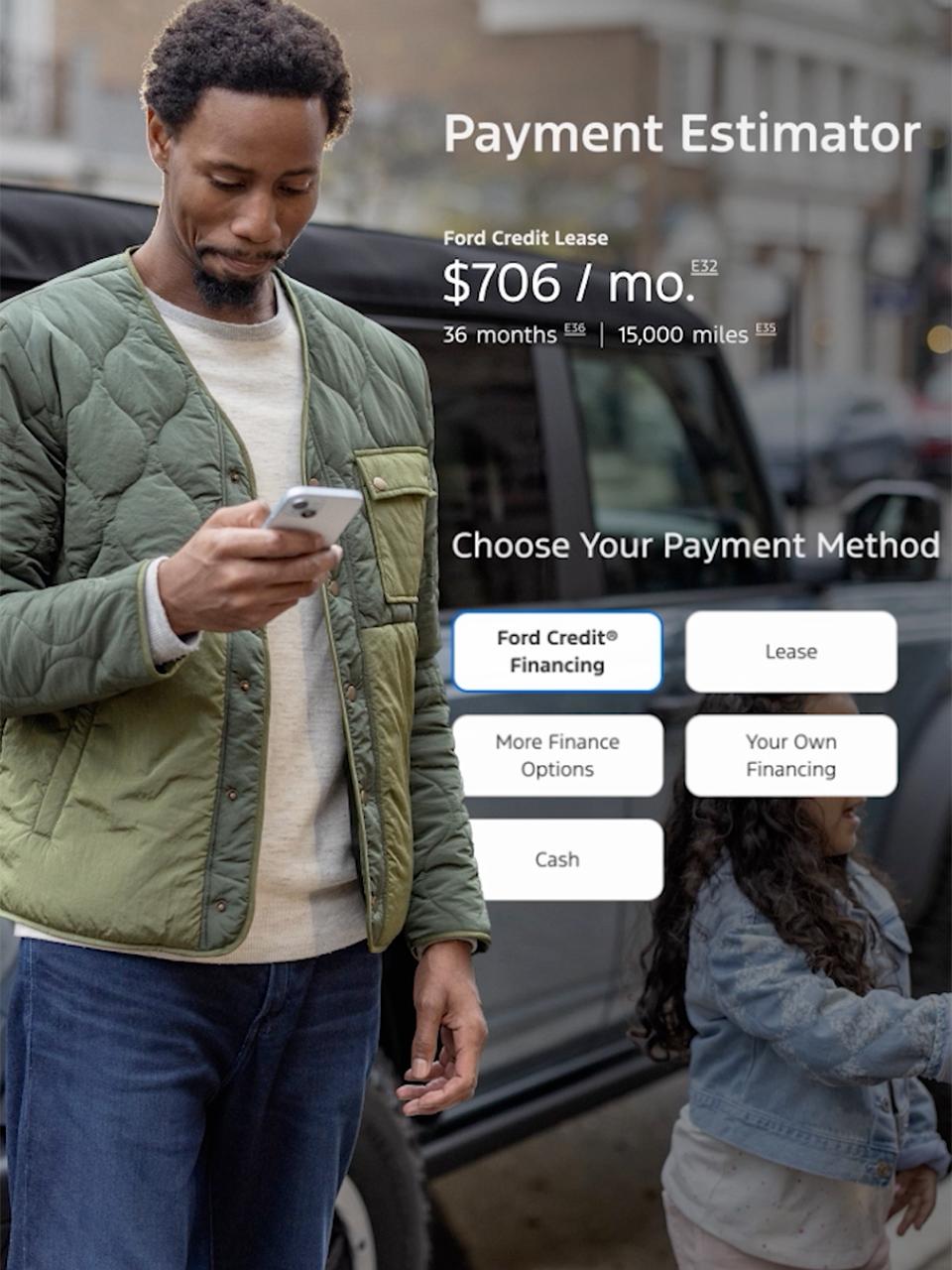 A man looks at his phone while standing beside his Ford Bronco®