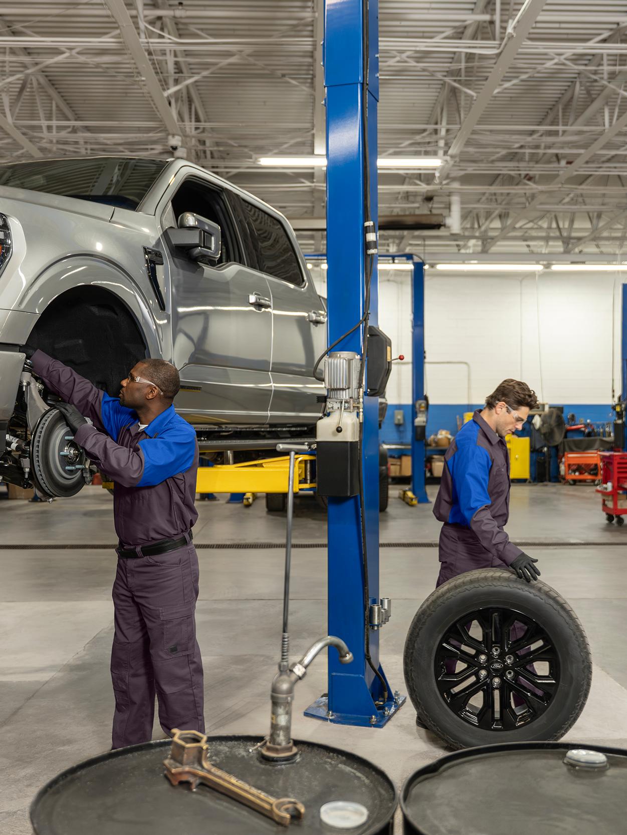 Two Ford Service technicians service a Ford vehicle in the service bay