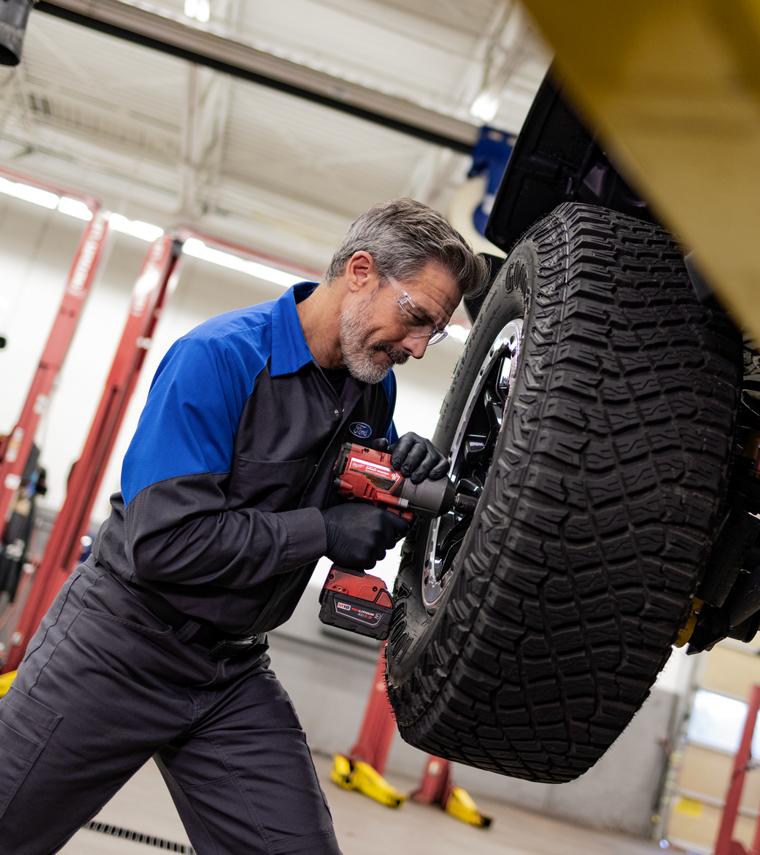 A Ford mechanic working on the tires of a Ford vehicle.