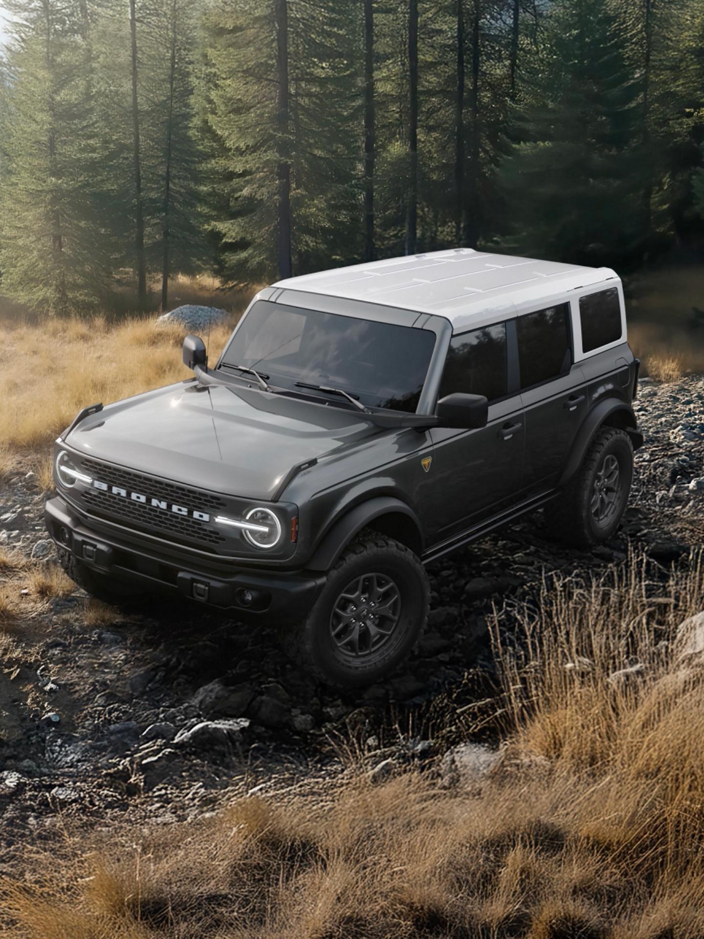 A 2026 Ford Bronco® SUV on a muddy path, with a dark-colored body and a white roof