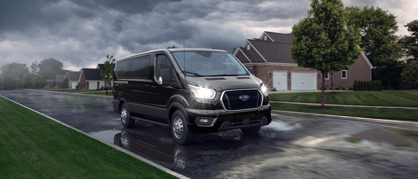 A 2025 Ford Transit® van is driving down a rainy street