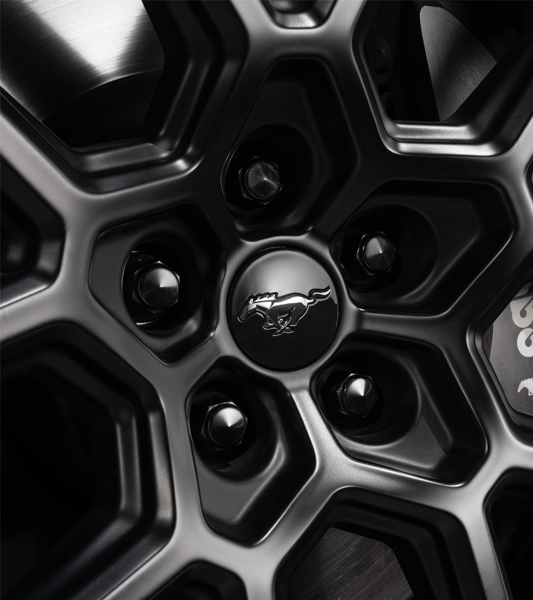 Close-up of the black lug nuts and Mustang center cap on the R1 wheel