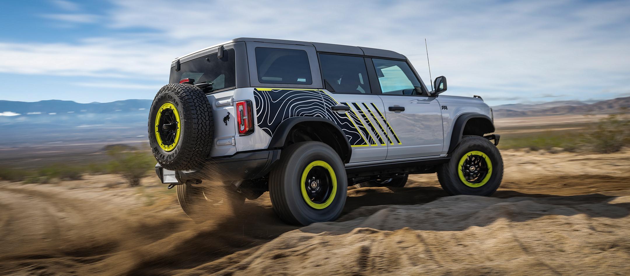 A 2027 Ford Bronco® RTR model kicking up dirt near a large rock pile