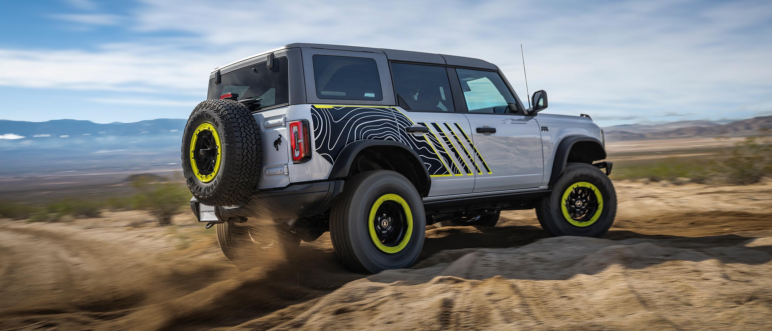 A 2027 Ford Bronco® RTR model kicking up dirt near a large rock pile