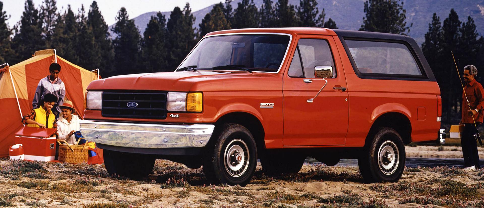 An orange 1987 Ford Bronco® model parked at a campsite