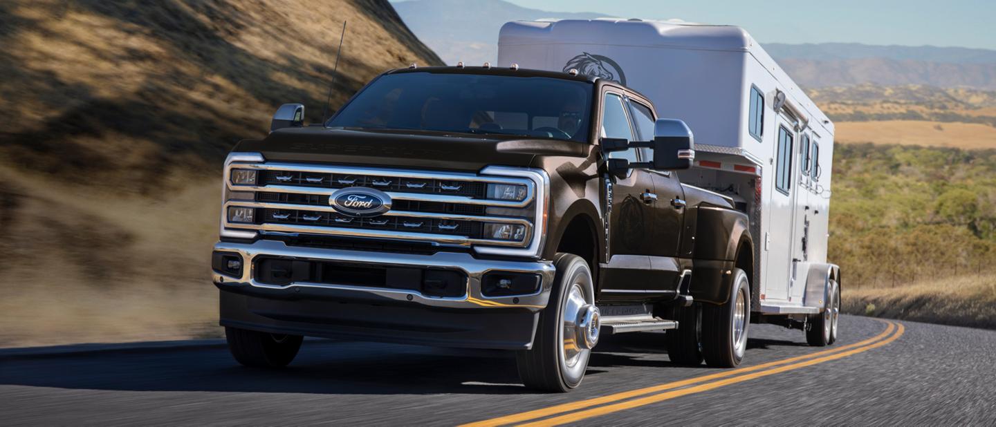 2025 Ford Super Duty® F-350® LARIAT DWR in Dark bronze Metallic pulling a horse trailer