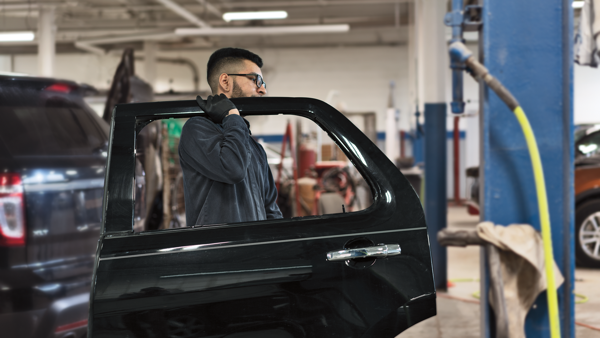 A Ford Service technician carries a door for a vehicle