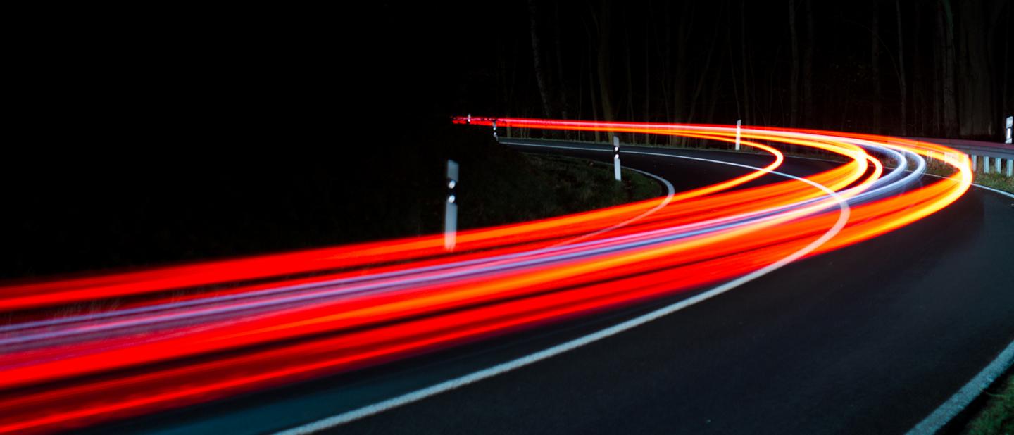 Taillight streaks on a curving highway.