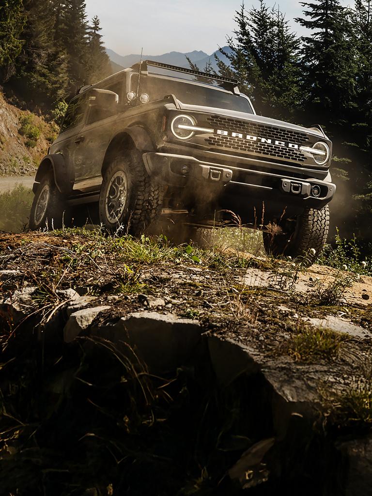 A 2025 Ford Bronco® Badlands® SUV being driven up a muddy, rocky hill