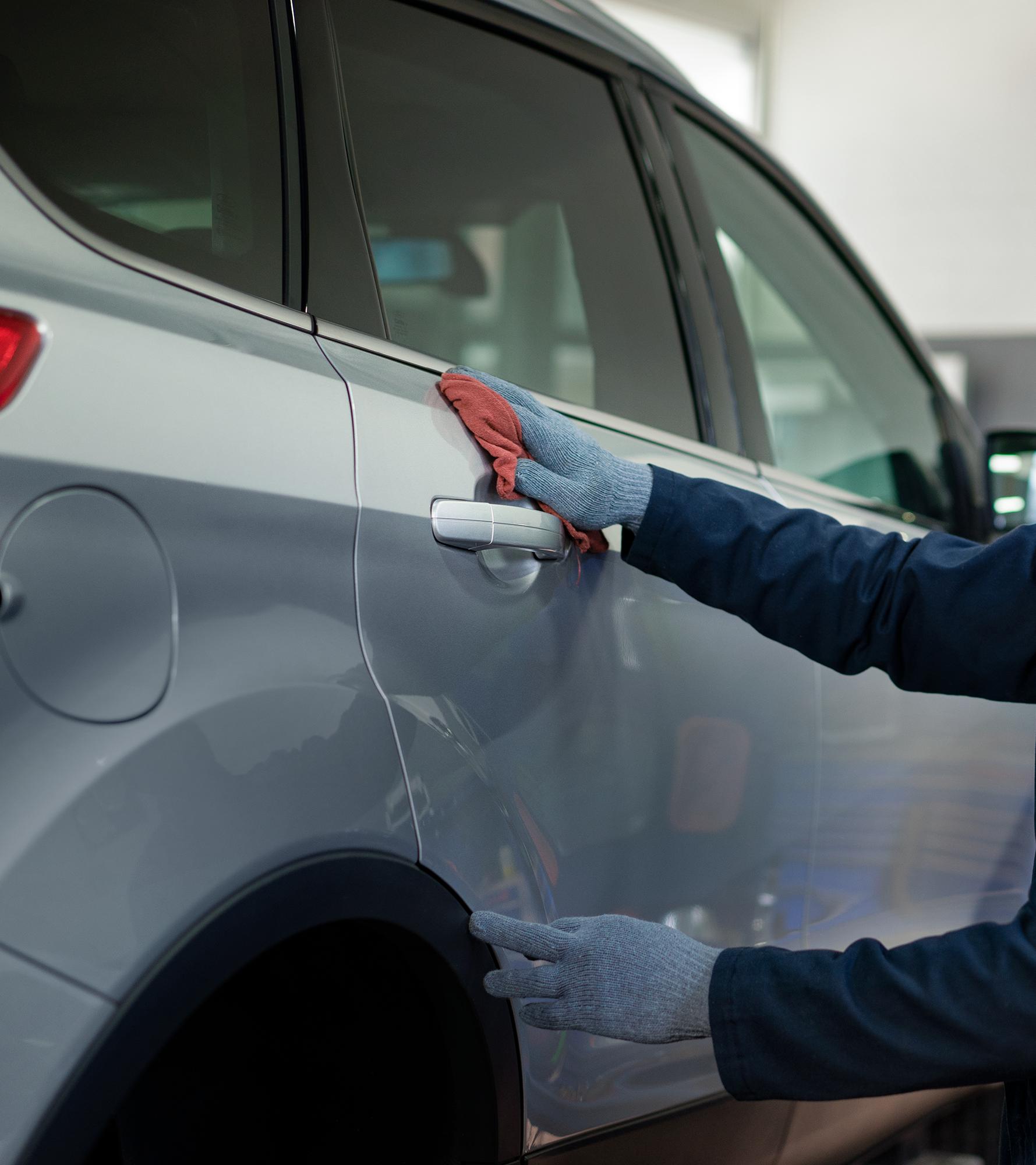 A Ford technician checks the finish on a door