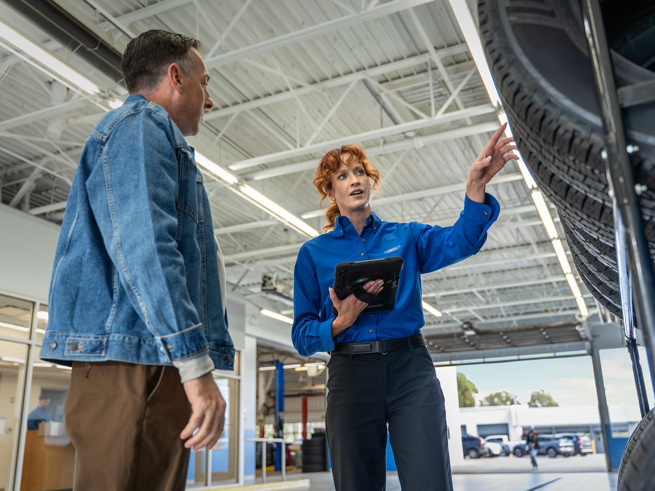 A Ford Service sales rep looks at tires with a Ford customer