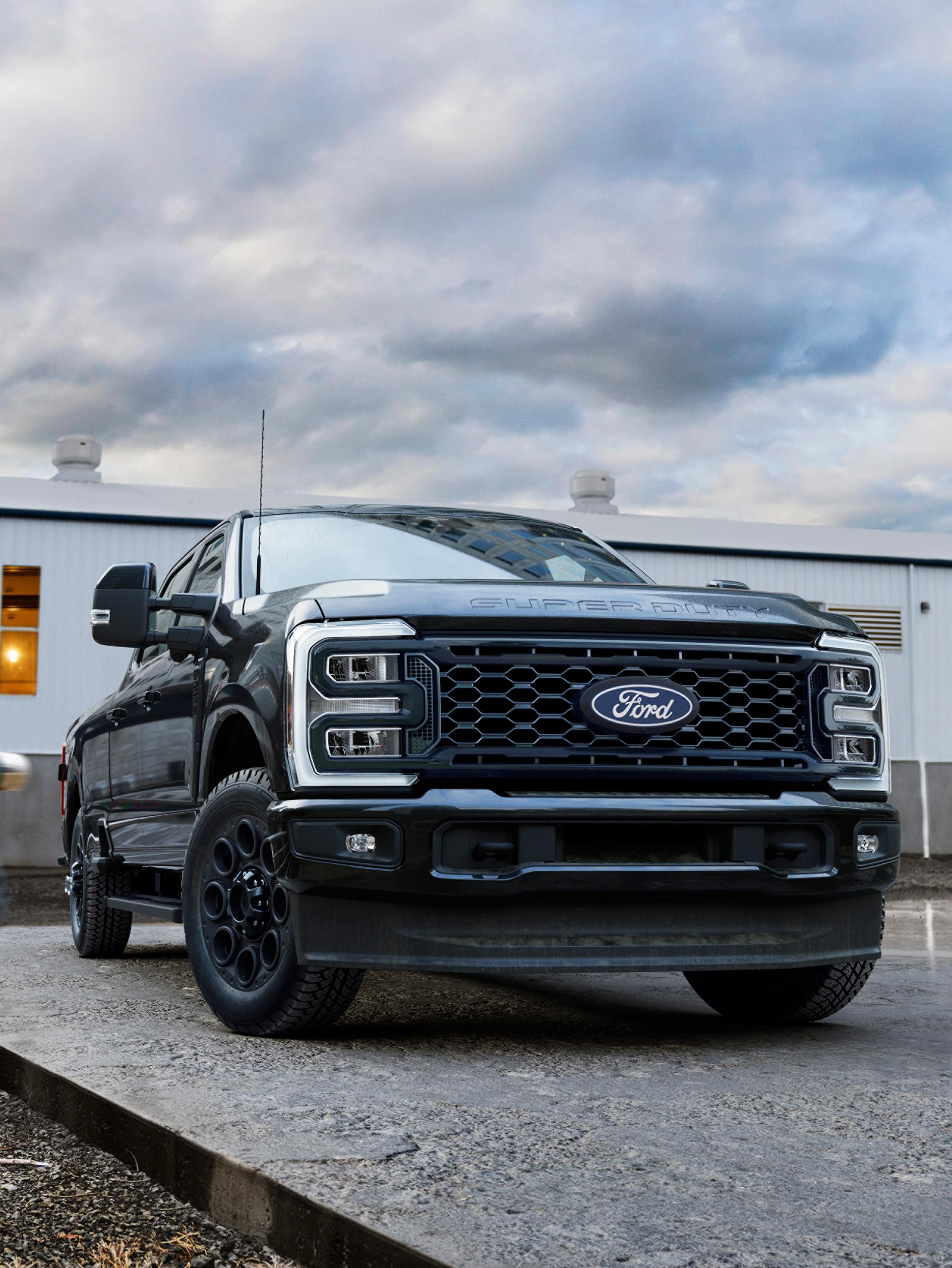 2027 Ford Super Duty® with the Black Appearance Package parked on a cement slab with a person walking toward it
