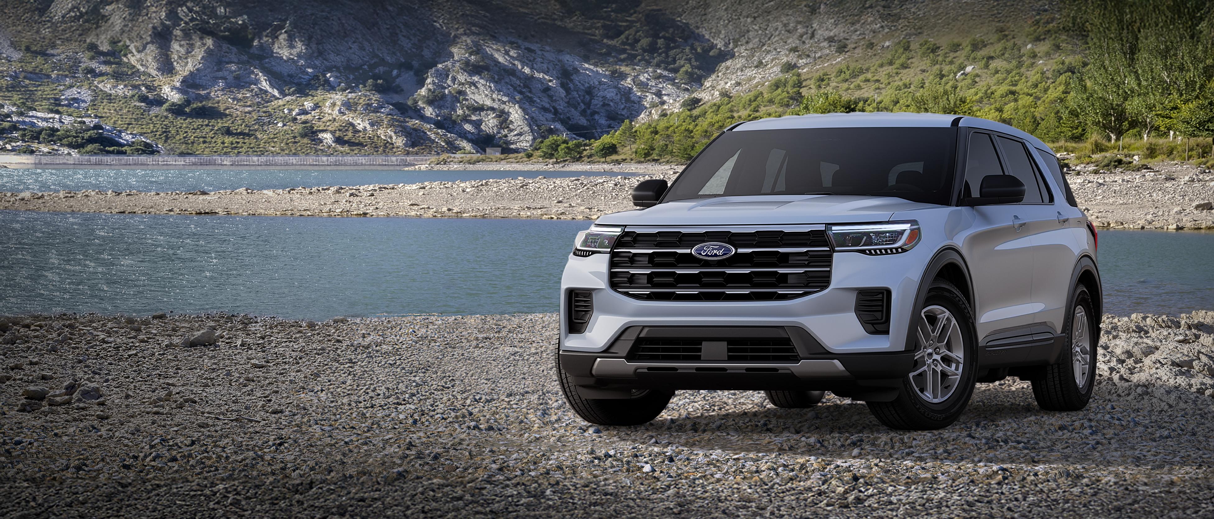 Un modelo Ford Explorer® Active 100A 2026 estacionado en una extensión rocosa cerca de un lago de montaña