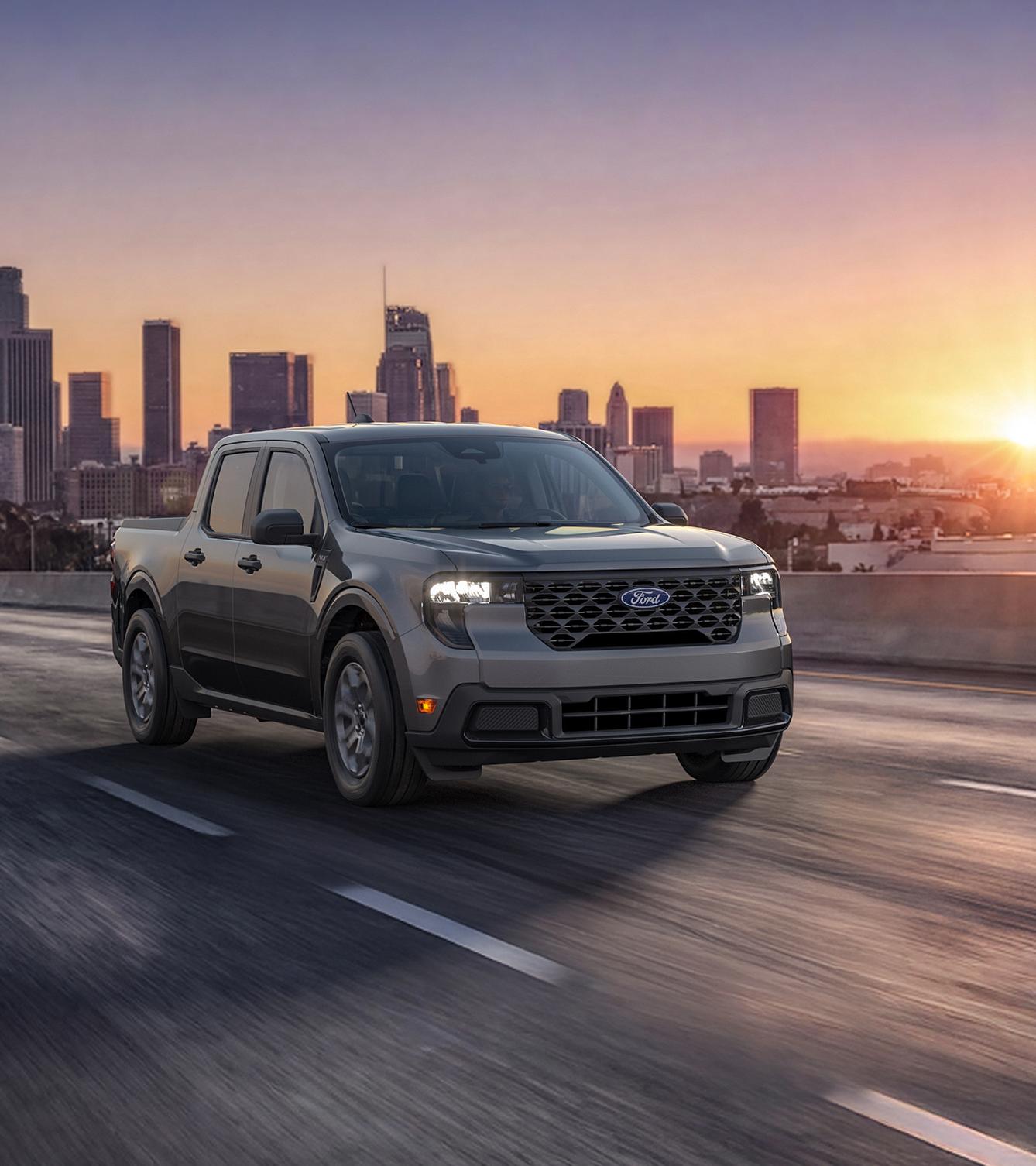 2026 Ford Maverick® XLT hybrid truck driving on a road with a cityscape background