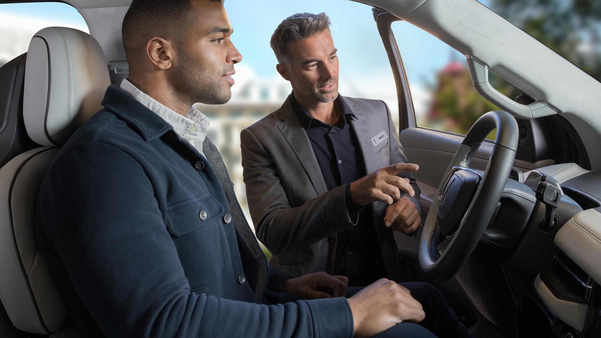 One man sits in a 2026 Lincoln Black Label Navigator while another stands at the open door, pointing to the panoramic display