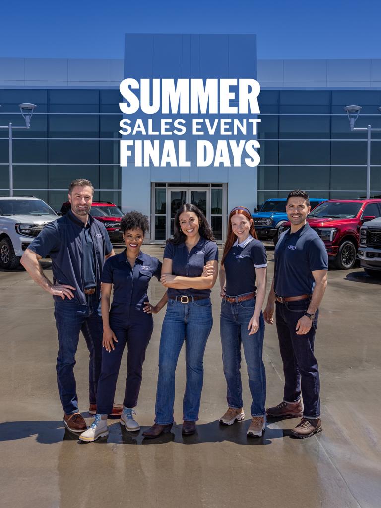 Group of employees standing in front of a Ford dealership