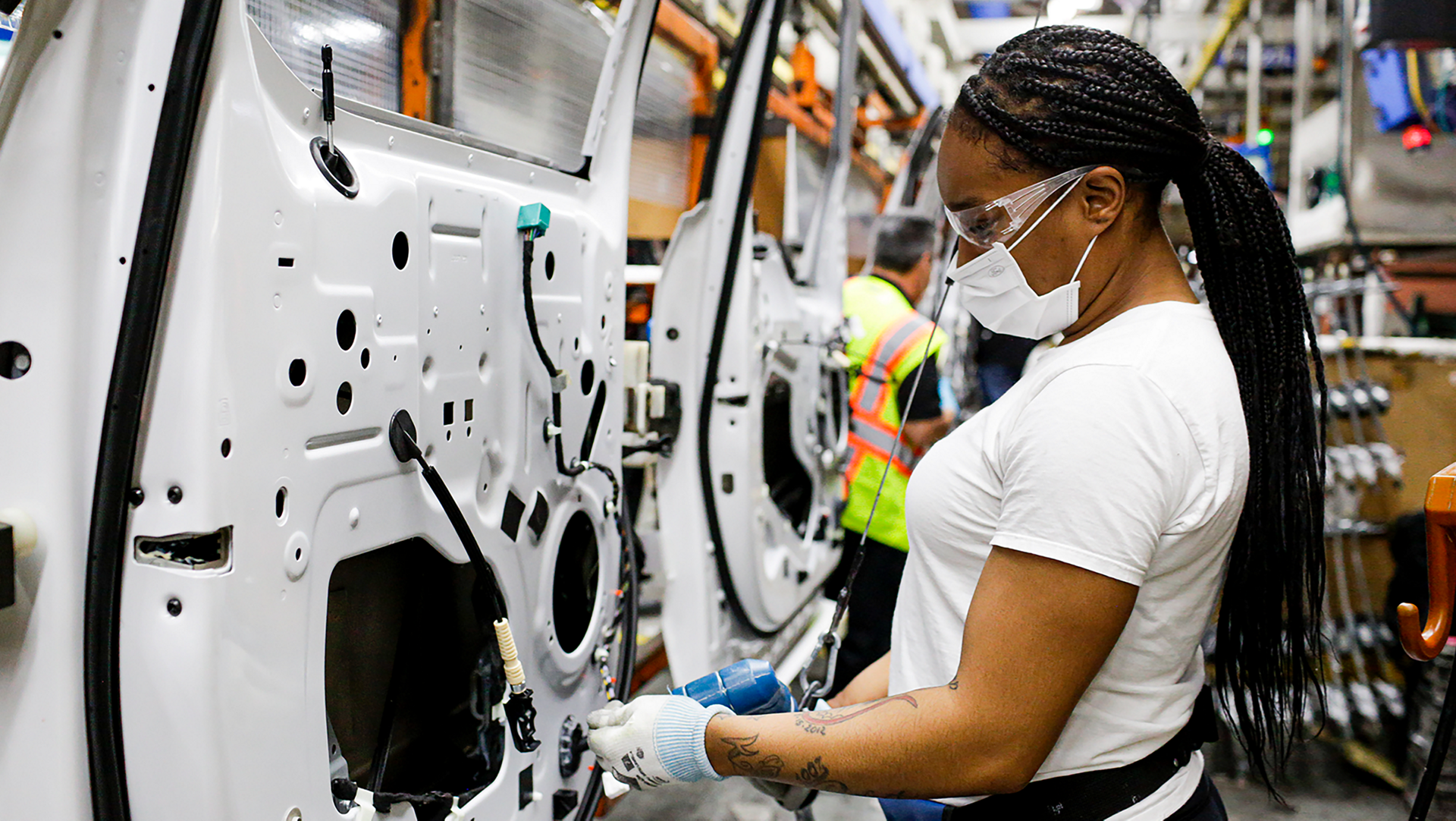 People working on vehicle doors on assembly line