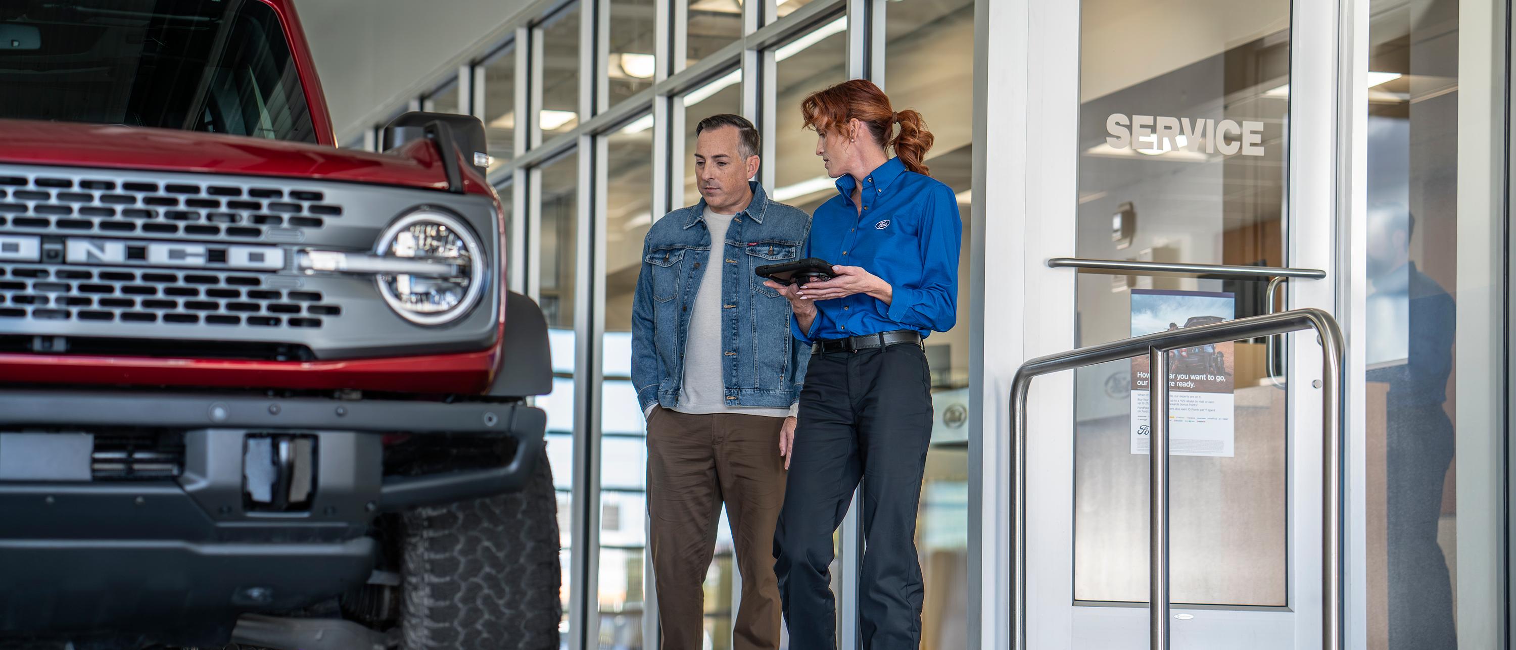 A Ford Service representative walks a customer through their maintenance needs