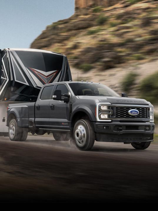 A wide angle shot of a Ford truck towing a Camper along a mountain range.