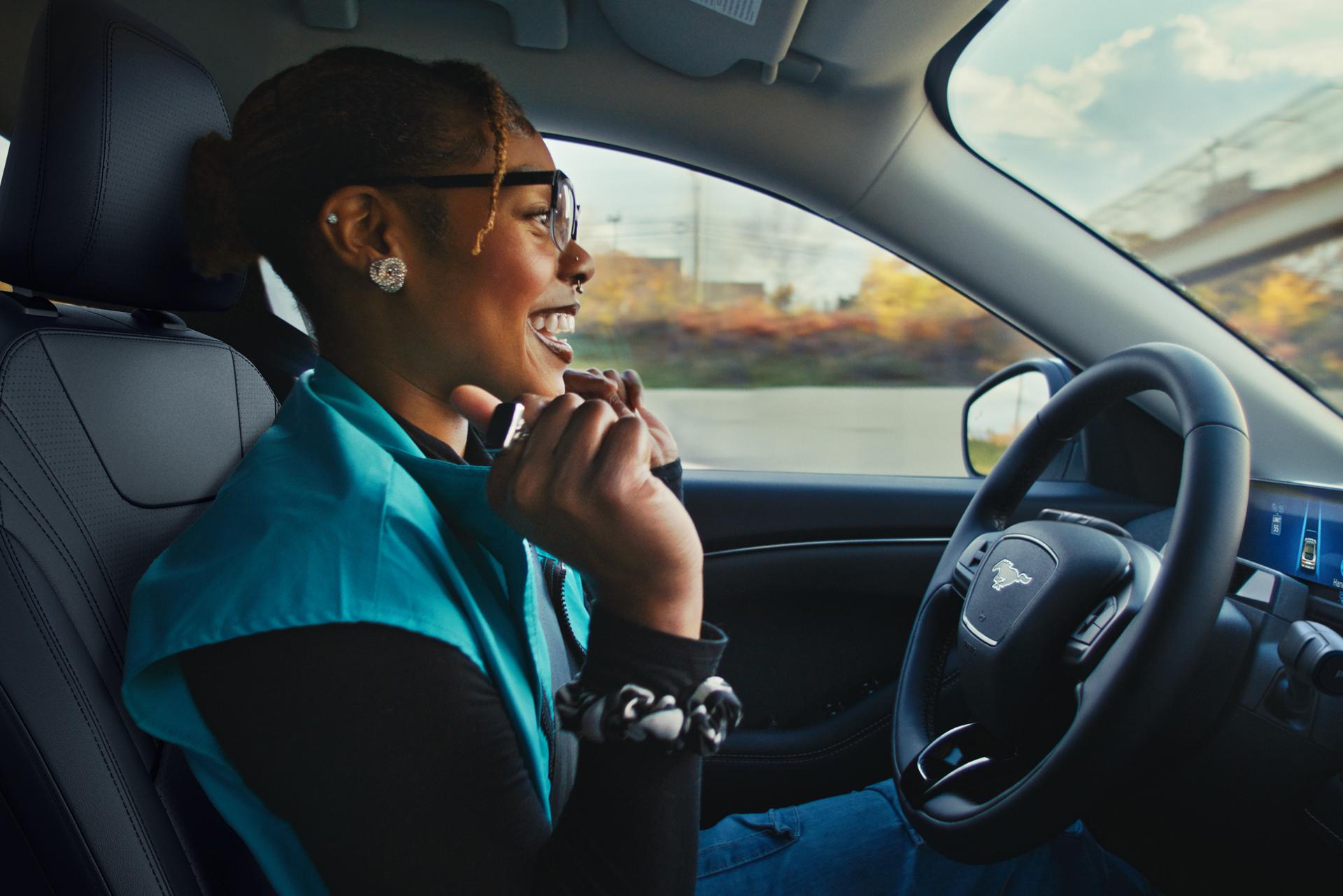 A Ford Mustang® Mach-E® SUV owner using BlueCruise raises their hands off the wheel and smiles in delight