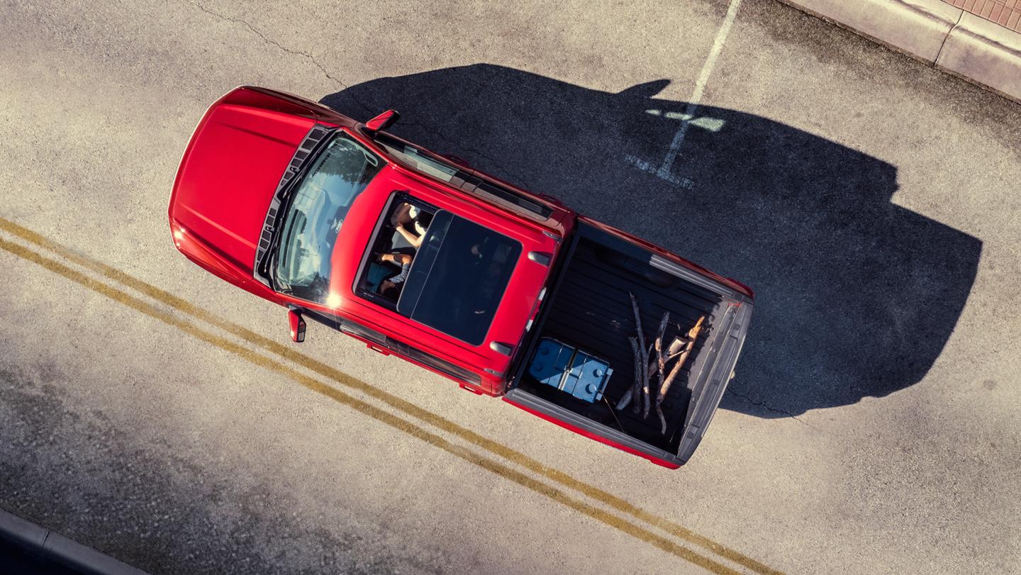 An aerial view of two people in a 2025 Ford F-150® Lightning® featuring the sunroof and cargo in the truck bed