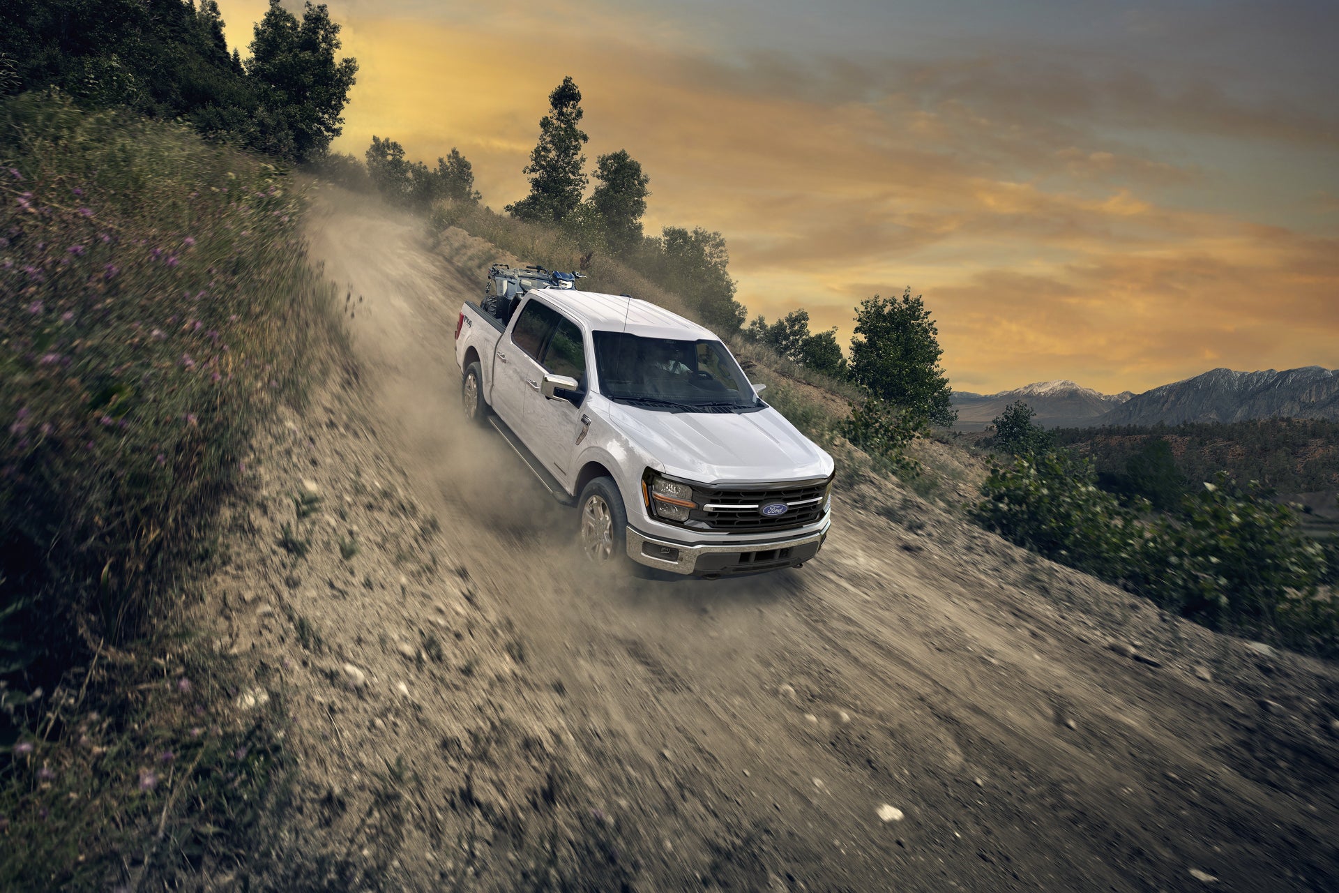 White Ford F-150 XLT climbing a dusty dirt trail at sunset
