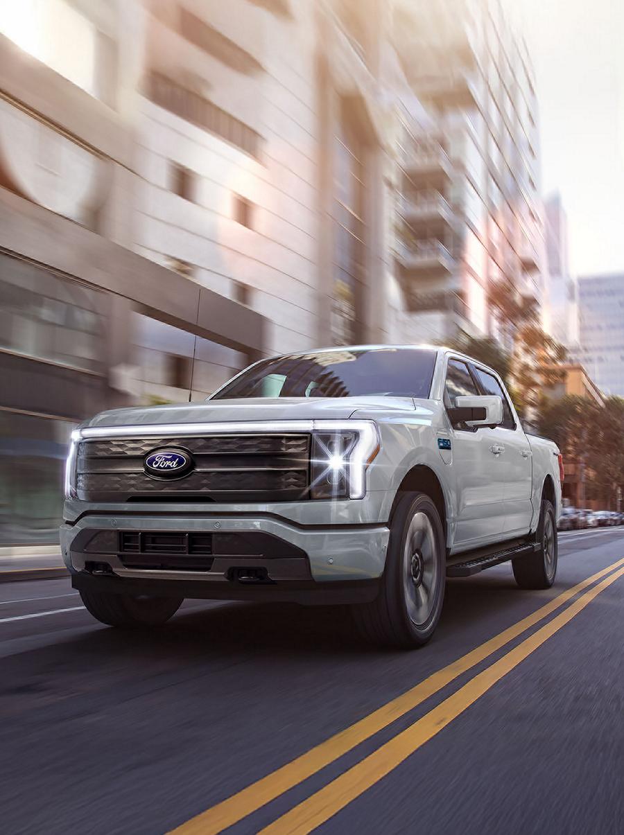 A 2025 Ford F-150® Lightning® pickup driving down a city street