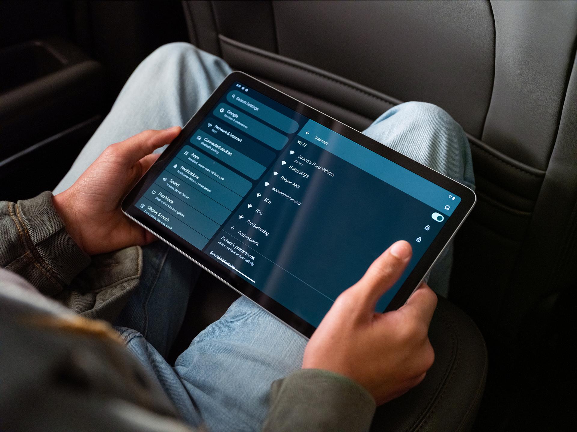 A passenger using a tablet in the rear seat of a 2026 Ford Bronco® SUV
