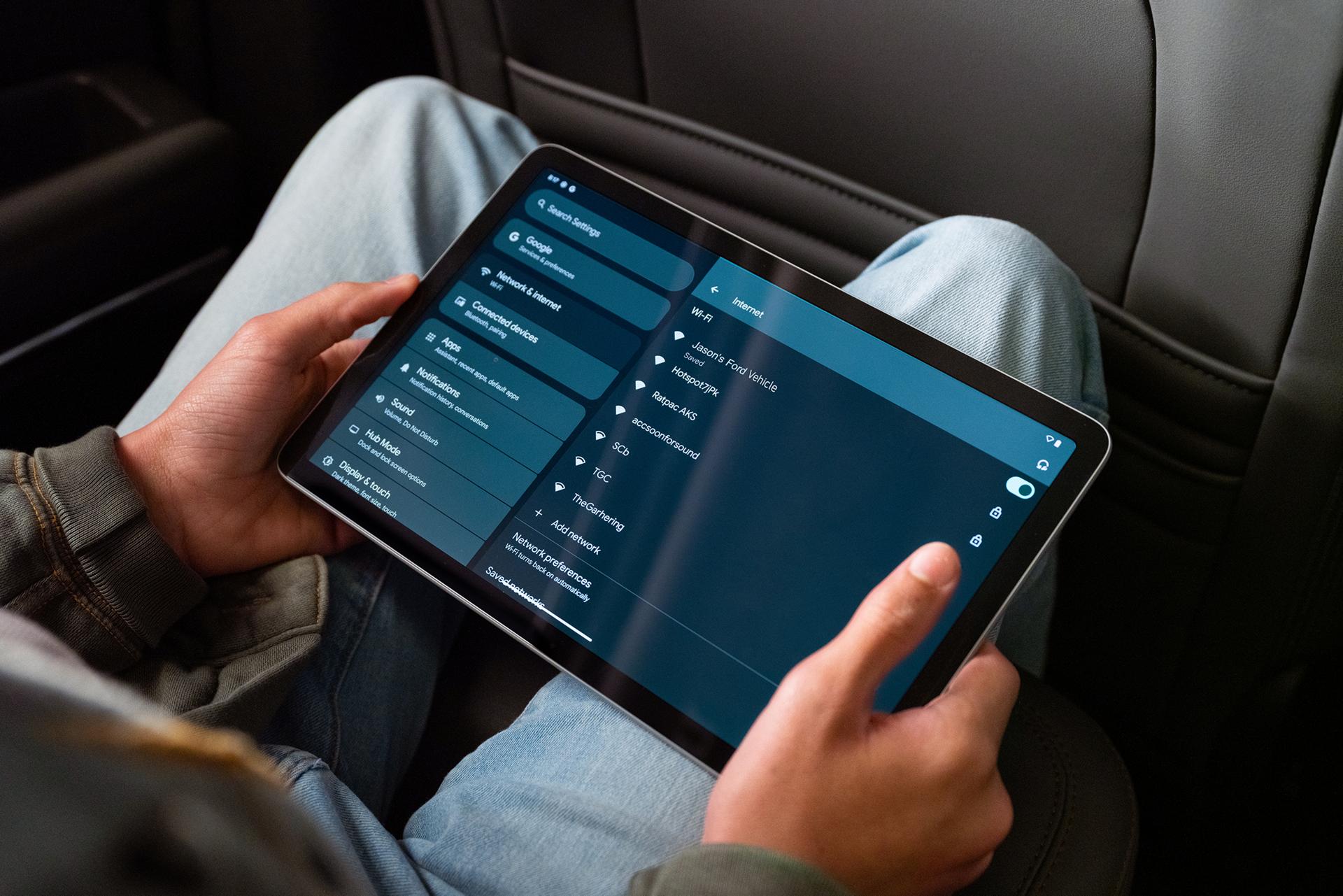 A passenger using a tablet in the rear seat of a 2026 Ford Bronco® SUV