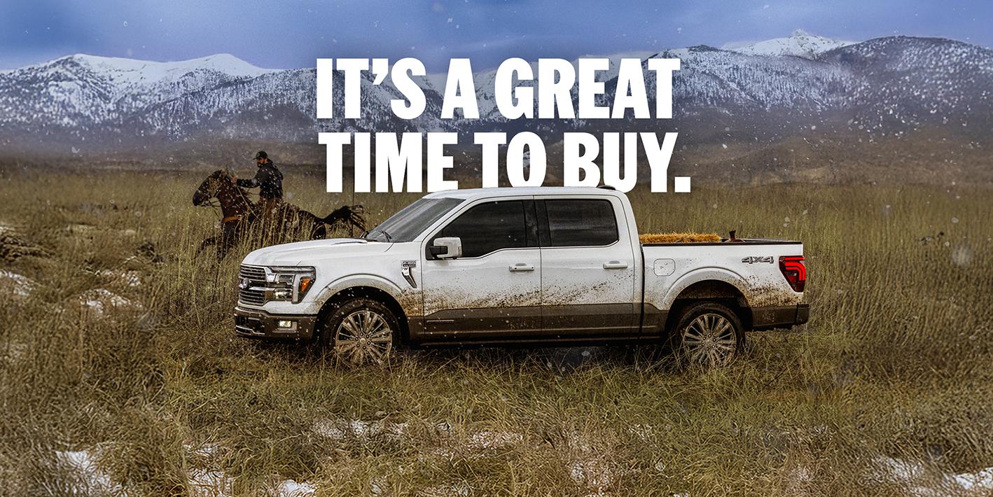 A white 2025 Ford F-150® King Ranch® model being driven through a field next to a man on a horse with a mountain range in the background