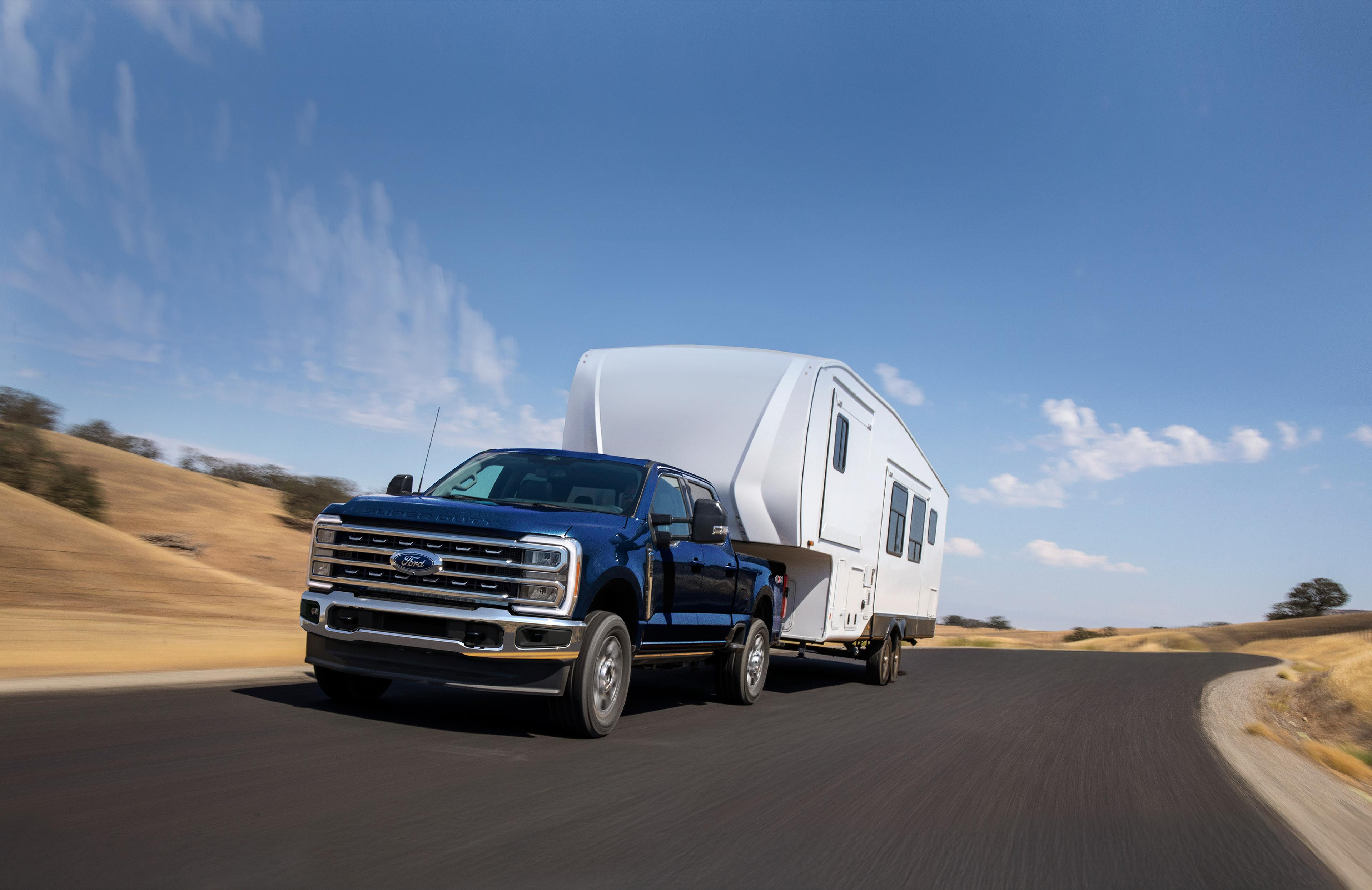 2025 Ford Super Duty® F-250® Lariat® model in Antimatter Blue pulling a large camper on a paved road