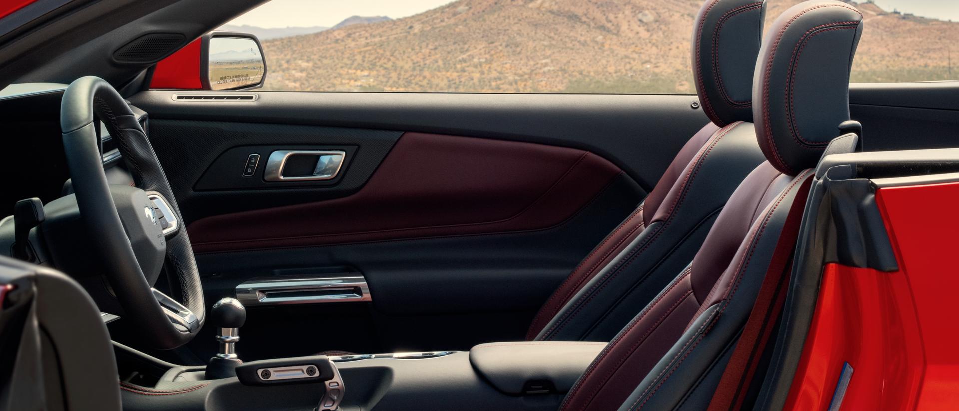 Parked 2026 Ford Mustang® convertible with the driver's side door open showing the available Carmine Red interior