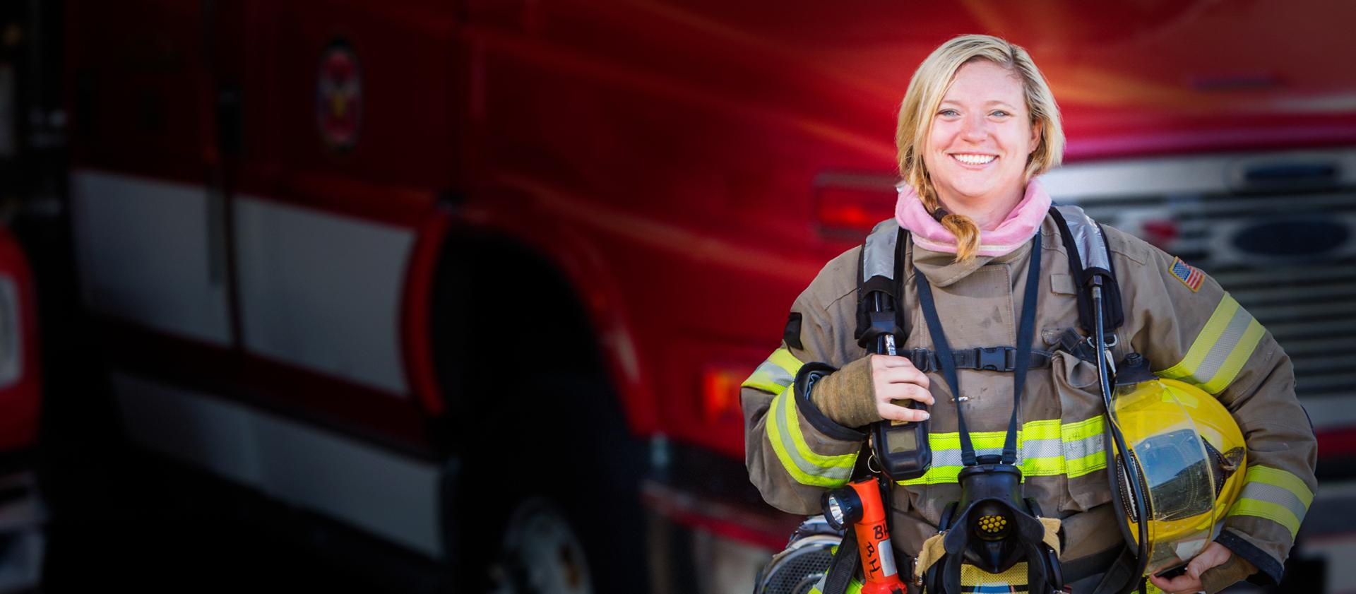 Smiling firefighter in front of a red Ford emergency vehicle