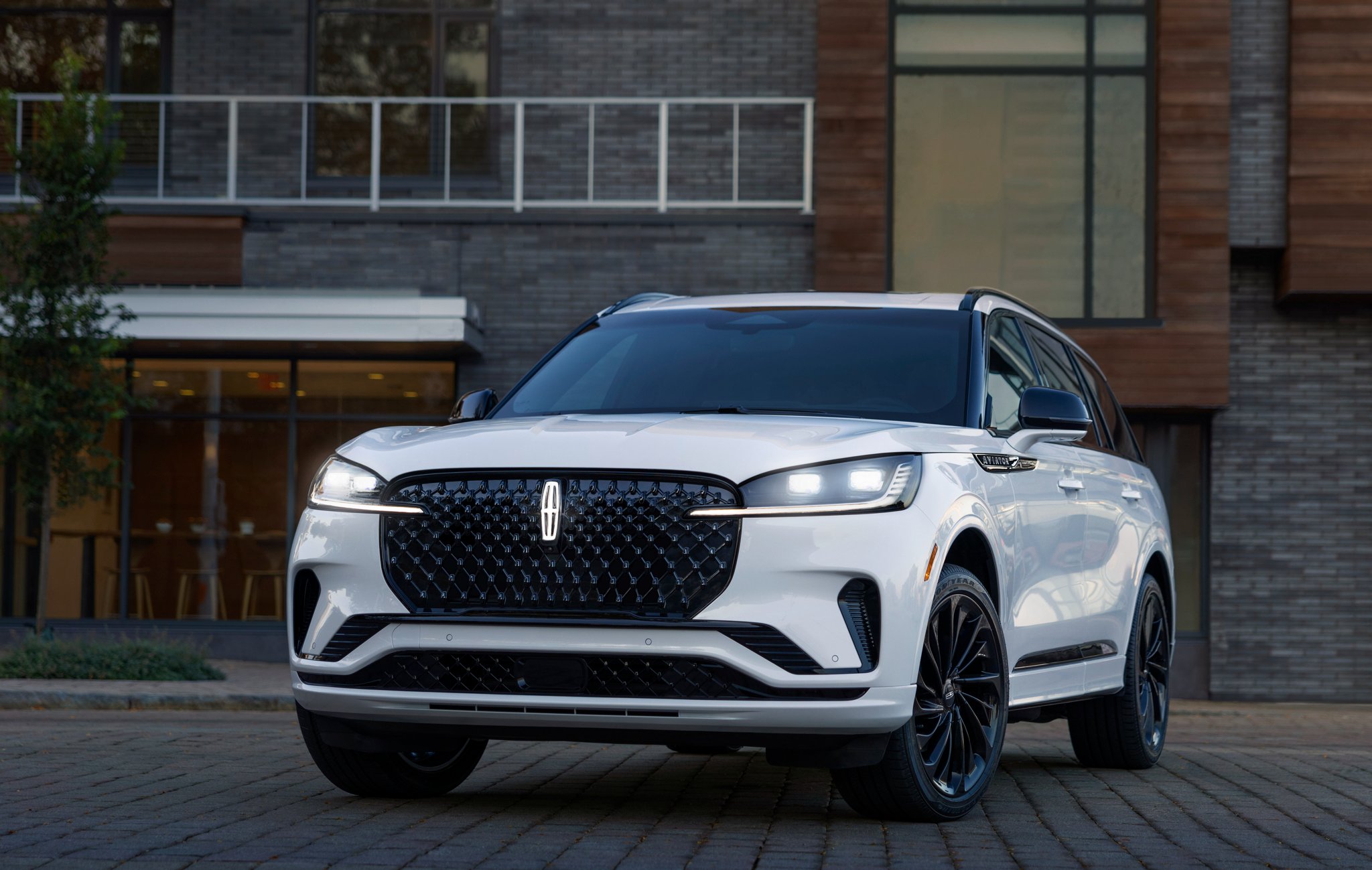 Un Lincoln Aviator Ultra 2025 est stationné devant un restaurant avec ses phares allumés