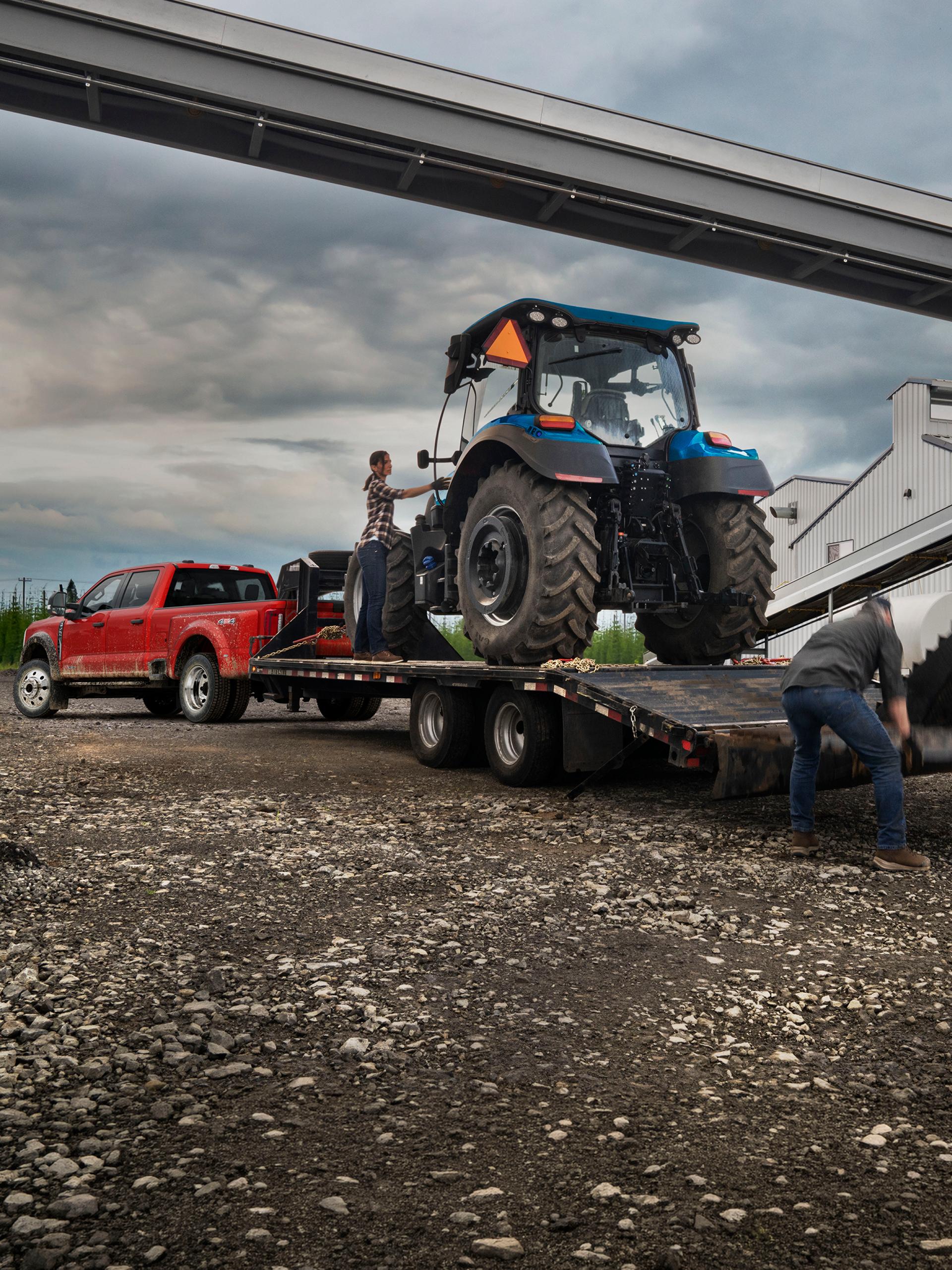 2027 Super Duty® F-450® XL pickup in Race Red pulling a trailer carrying a large tractor