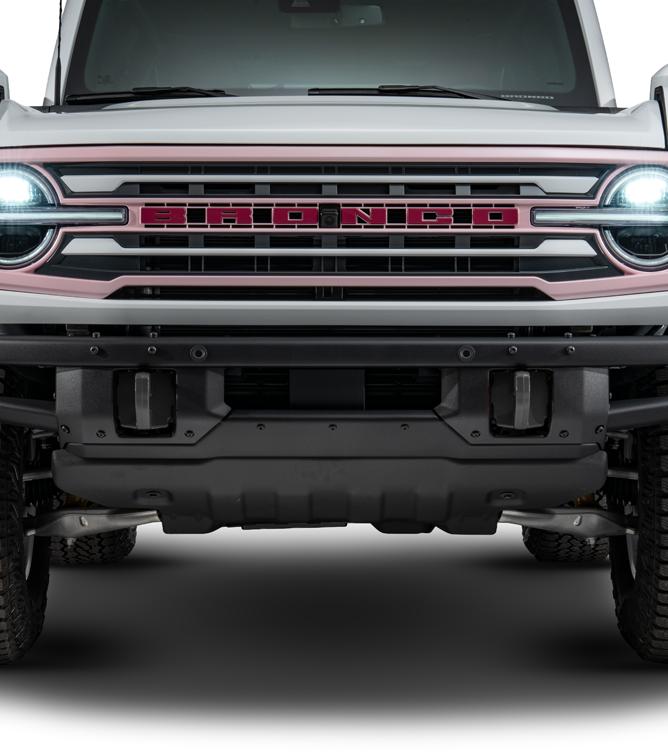 Front view of a white Bronco showing the modular front bumper and grille with painted Bronco lettering