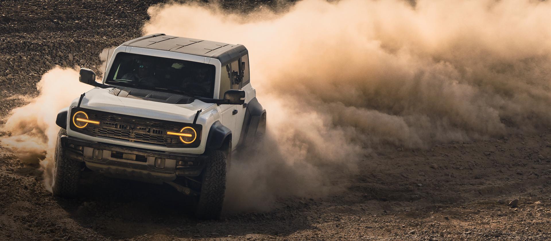 A 2026 Ford Bronco® SUV kicking up dust on a rocky landscape