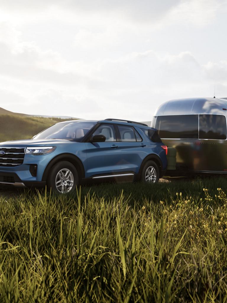 A 2026 Ford Explorer® Active model hitched to a travel trailer, parked in a field