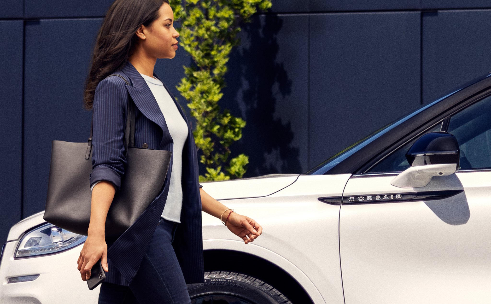 A person approaches a 2026 Lincoln Corsair® Reserve model while holding a mobile phone