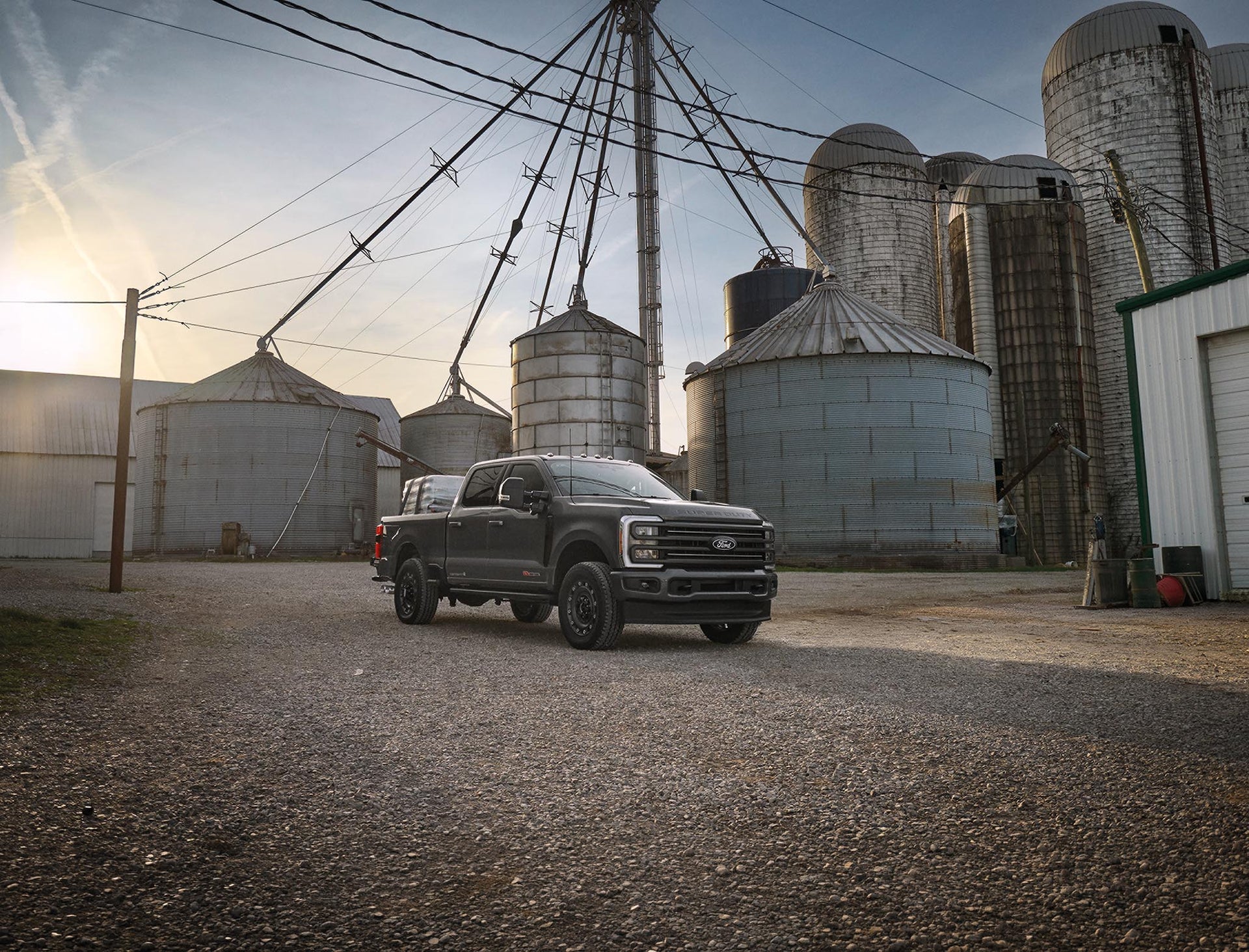 Dark gray Ford Super Duty F-350 XLT parked by grain silos on a farm