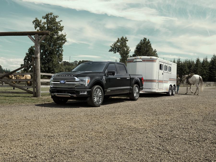 2025 Ford F-150® Platinum® in Agate Black parked with a trailer on a horse farm