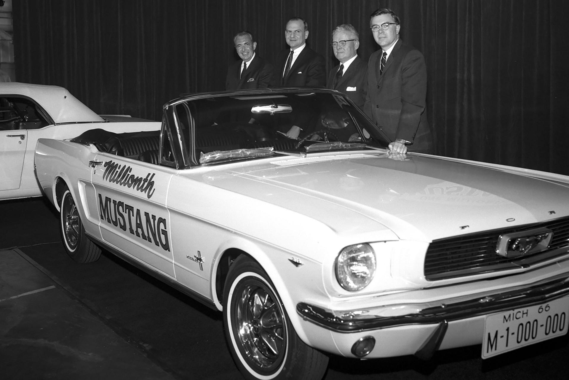 Four men posing in front of a Mustang car