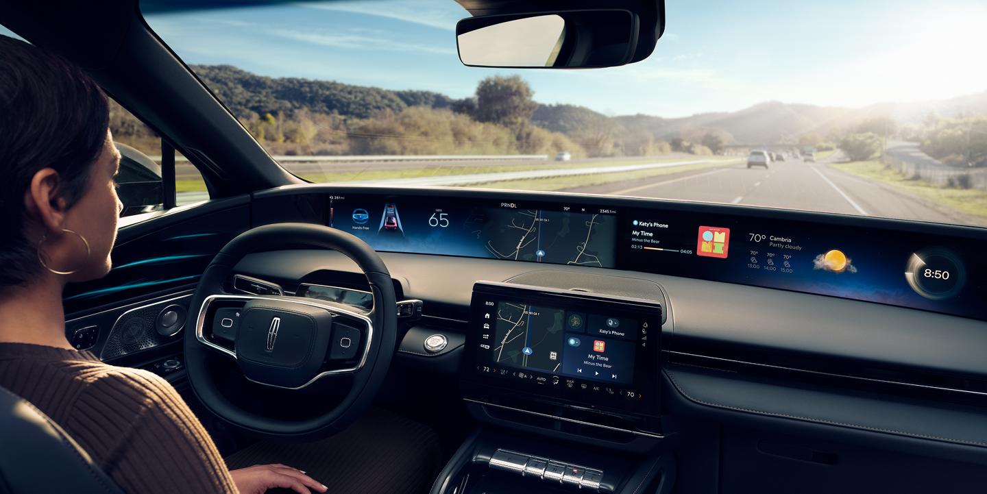 A woman is shown driving Lincoln Nautilus SUV hands-free using Lincoln BlueCruise on a highway.