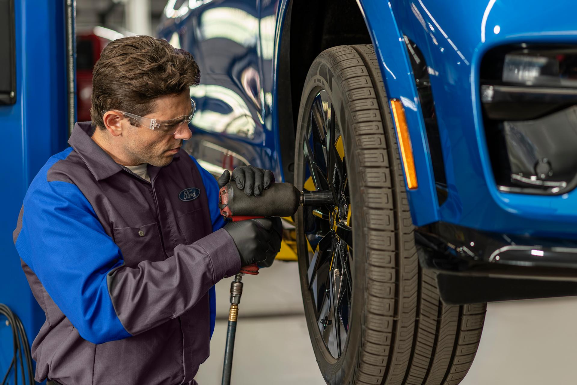 A Ford Service technician puts a new tire on a Ford vehicle