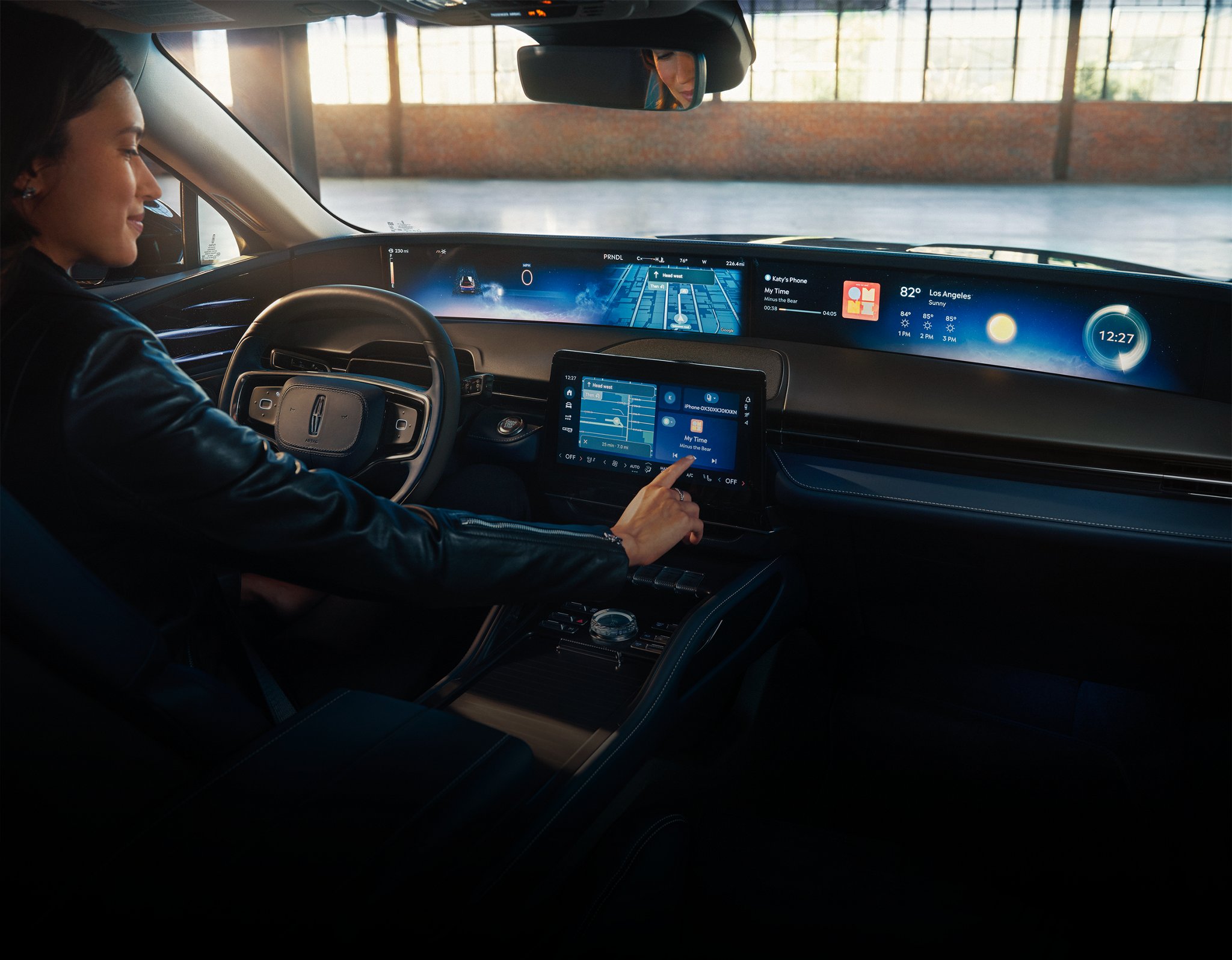 A person operates a Lincoln vehicle while tapping the center-stack display touchscreen.